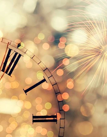 A vintage clock shows midnight with fireworks in the background, symbolizing a New Year celebration.